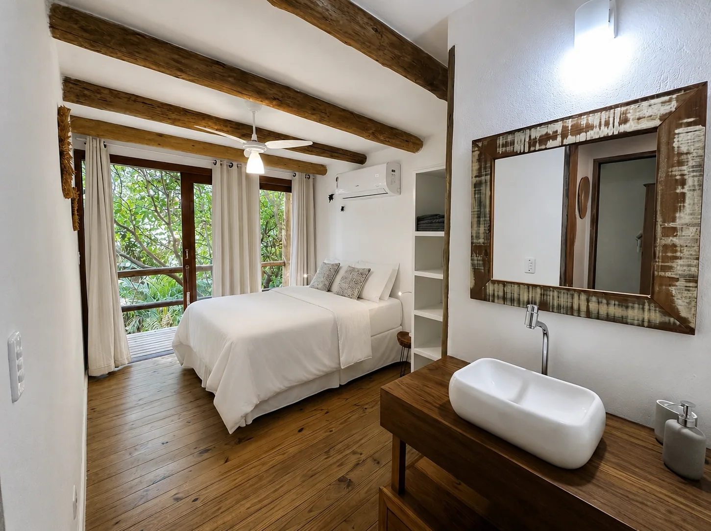 Suíte da Casa de Baixo na Casa da Árvore, Praia do Rosa, cama de casal grande, ventoinha de teto, ar condicionado, decoração de palha e porta envidraçada para varanda na mata.