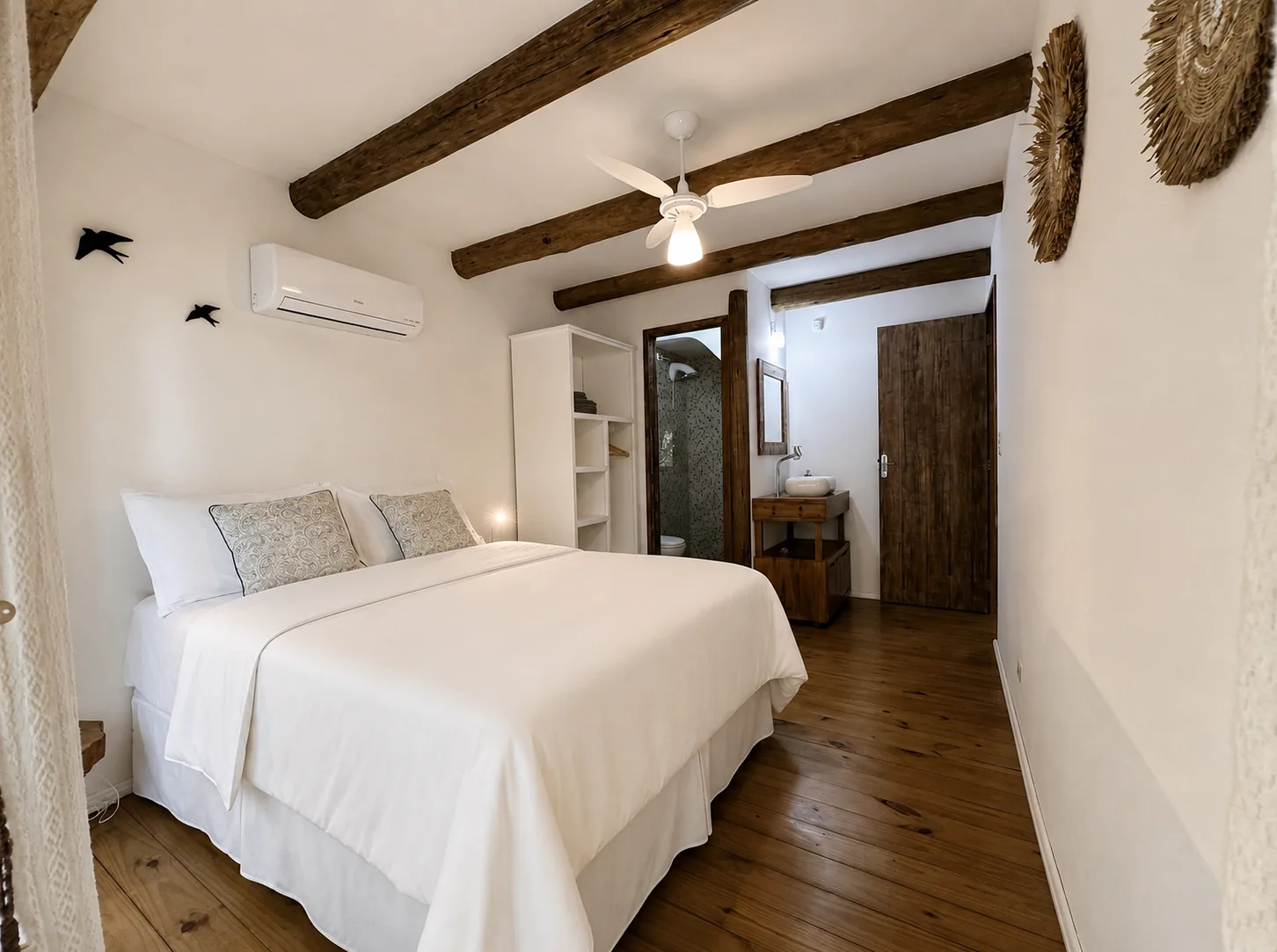 Suíte com cama de casal e porta para a varanda na mata.